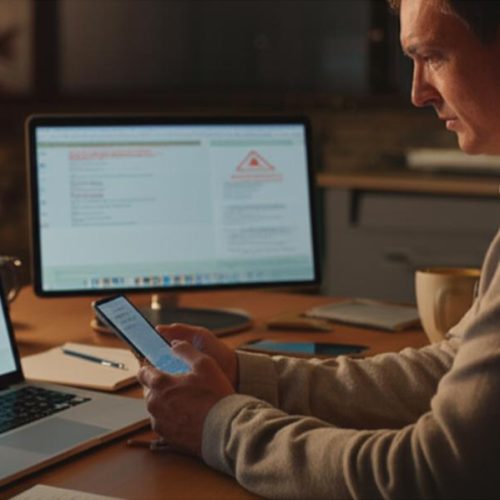 Usuário atento diante de dispositivos digitais, simbolizando vigilância e prevenção contra fraudes online.